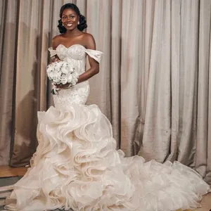 Détail d'une robe de mariée sirène avec traîne à volants et décolleté épaules