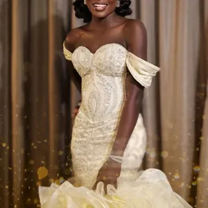 Vue détaillée de la robe de mariée à épaules dénudées avec broderie et traîne à volants.
