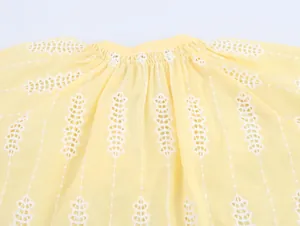 Gros plan sur la broderie anglaise blanche complexe d'un chemisier jaune de style français