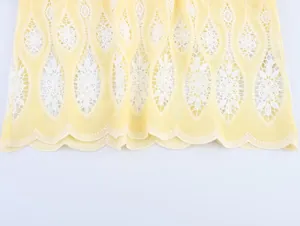 Détail de la broderie ajourée blanche sur l'ourlet festonné du haut jaune