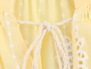 Gros plan sur la broderie blanche et le lien en coton d'un haut jaune de style français