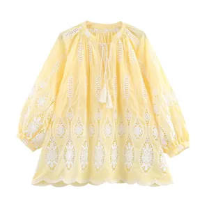 Blouse bohème jaune clair à broderie ajourée avec liens à pompons et coupe ample.