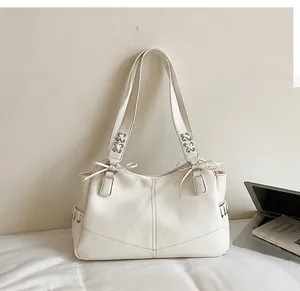 Détail rapproché d'un grand sac cabas en similicuir blanc avec des nœuds décoratifs