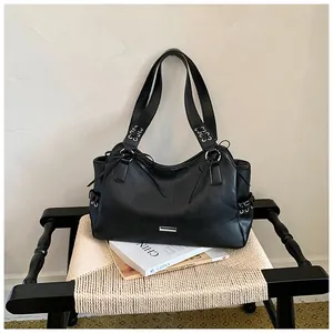 Grand sac cabas en cuir PU noir avec œillets sur une chaise en osier tressé