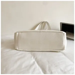 Vue détaillée de la base large et des coutures d'un sac cabas blanc en cuir PU