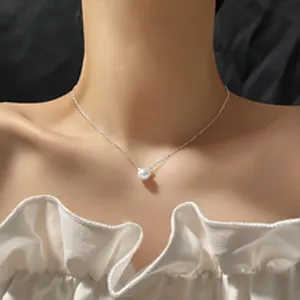 Gros plan d'un délicat pendentif muguet blanc sur le cou d'un mannequin, chaîne argentée