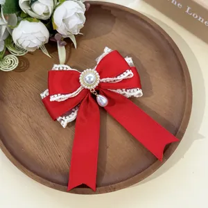 Macro view of a sweet red lace bow hair clip with a pearl pendant on a wooden tray