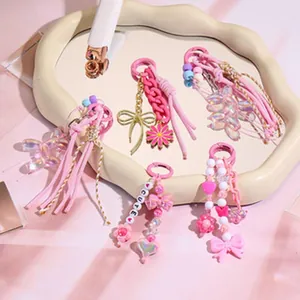 Close-up of pink Y2K tassel earrings with beads, bows, and CUTE letter charms