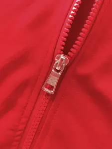 Macro view showing the smooth red resin zipper detail on premium men's athletic jacket