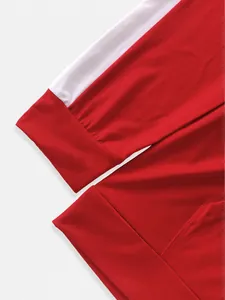 Detailed close-up of red and white sporty jacket sleeve cuff and pocket stitching.