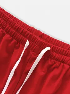 Close-up of red men's sports joggers featuring elastic waistband and white drawstring