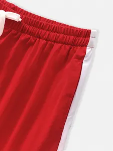 Close-up detail of red sports pants showing elastic waistband and white side stripe detail.