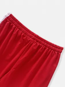 Close-up of elastic waistband on red sports pants with white side stripe detail