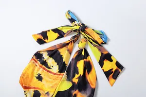 Close-up detail of a vibrant yellow abstract print halter neck top with tie-knot design