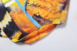 Detail of the vibrant yellow and orange tie-dye print with contrasting light blue straps