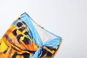 Macro shot of vibrant tie-dye printed fabric showing the intricate knot detail of the skirt.