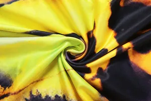Detailed macro shot of vibrant yellow and black tie-dye fabric showing smooth silky texture