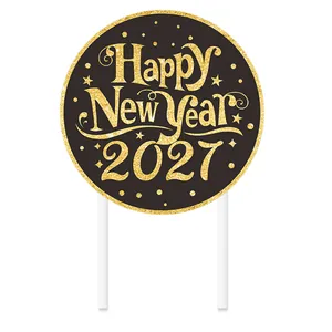 Close-up detail of a gold glitter Happy New Year 2027 cake topper on black background