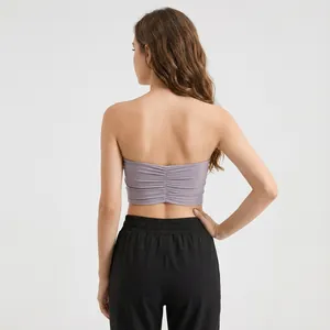Back view of a women's purple ruched sports bra paired with black athletic pants