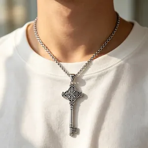 Vintage stainless steel key pendant necklace with ornate cross motif on male model.