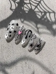 Macro view of Halloween ghost and spider web patterns on stiletto press-on nails