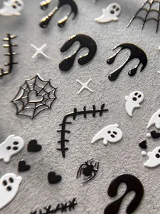 Macro detail of embossed 3D Halloween nail stickers with ghosts and spider webs.