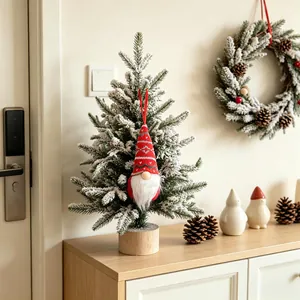 Handmade red knitted Christmas gnome ornament hanging on a frosted festive tree