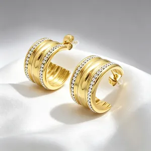 Detailed macro view of gold C-shaped titanium steel earrings with crystal pavé inlay