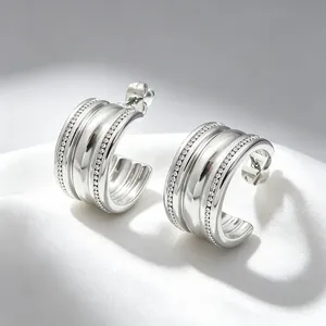 Close-up detail of silver-toned C-shaped earrings with sparkling pavé rhinestones