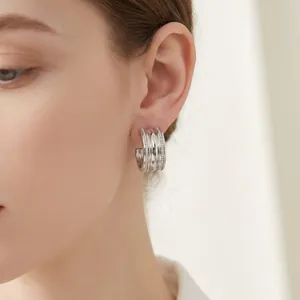 Close-up detail of a silver C-shaped titanium steel earring with four rows of pavé diamonds