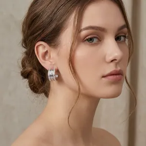 Close-up view of elegant silver C-shaped four-row diamond hoop earrings worn by a model