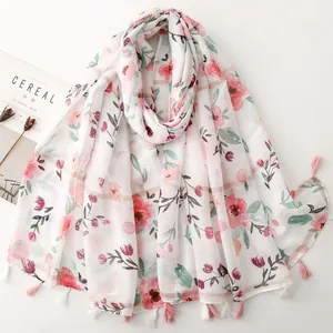 Close-up view of a white floral cotton linen feel scarf with pink tassels and metallic stripes