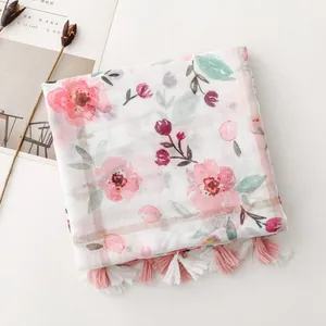 Detailed view of white floral scarf featuring elegant pink blossoms and playful tassels