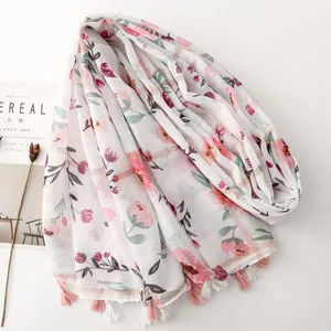 Close-up view of a white floral scarf featuring metallic silver thread and pink tassels