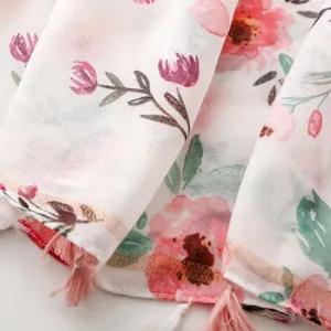 Detailed macro view of white floral scarf with pink tassels and metallic gold thread