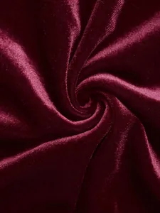 Macro view of luxurious burgundy velvet fabric showing elegant texture and soft drapes