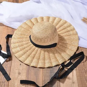 Vue détaillée d'un chapeau de paille pour femmes avec plis et ruban noir élégant.