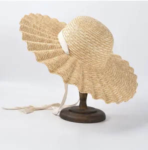 Vue détaillée d'un chapeau de paille à bord ondulé avec rubans blancs élégants.