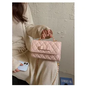 Elegante borsa a mano trapuntata rosa con fiocco e catena dorata indossata dalla modella.