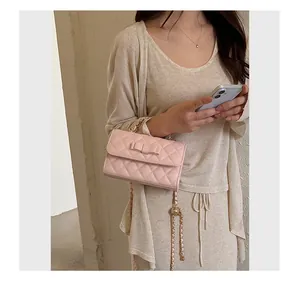 Dettaglio borsa rosa trapuntata con fiocco ed elegante tracolla a catena dorata.