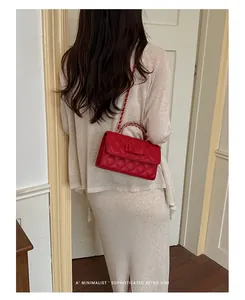 Vista dettagliata di una borsa trapuntata rossa con fiocco e catena indossata da modella.