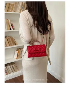 Elegante borsa trapuntata rossa con fiocco e catena dorata su una modella di moda.