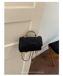 Vista dettagliata della borsa a catena trapuntata nera con fiocco elegante.