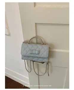 Dettaglio di una borsa trapuntata celeste con fiocco appesa a una maniglia.
