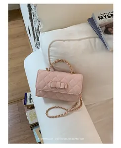 Dettaglio di una borsa trapuntata rosa con fiocco decorativo e catena dorata