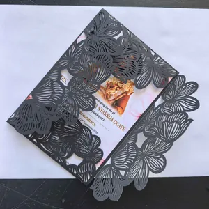 Close-up view of a black laser-cut floral invitation envelope showing fine hollow details