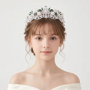 Dettaglio ravvicinato di una tiara da sposa vintage con perle bianche e accenti floreali verdi