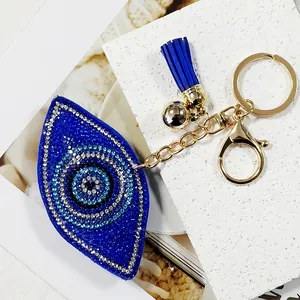Detailed close-up of blue rhinestone evil eye keychain with tassel and gold clasp