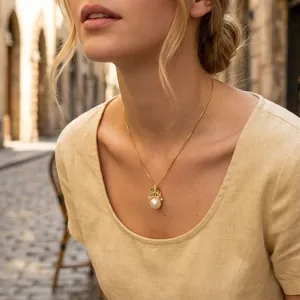 Detail of gold crown pendant with a large white freshwater pearl necklace on a model.