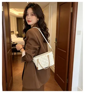 Élégant sac à bandoulière matelassé blanc pour femme porté avec un blazer marron chic
